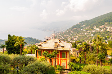 Fototapeta na wymiar Foggy panoramic view of Ligurian coastline landscape. Graduated green mountain chains full of small towns and villages. Liguria is a coastal region of north-western Italy.