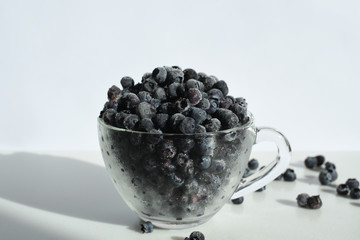 blueberries in a glass cup on white background.