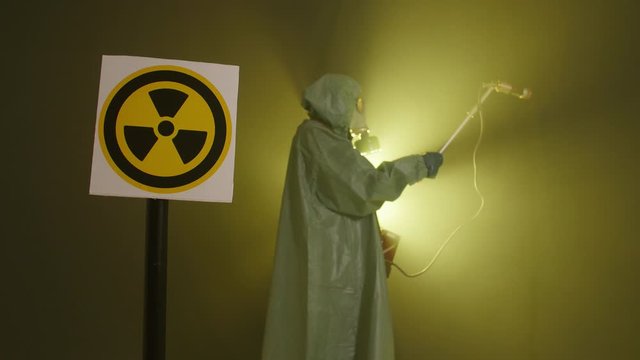 The concept of environmental disaster and radiation pollution. A man in a radiation protection suit measures radiation levels