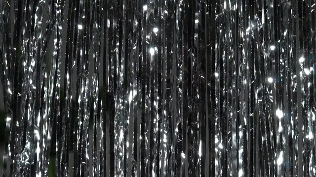 Silver rain from tinsel. Dynamic background in shining lights and sparkling particles. Beautiful silver background with shiny silver glitter sparkles. Festive mood. Christmas or holiday theme