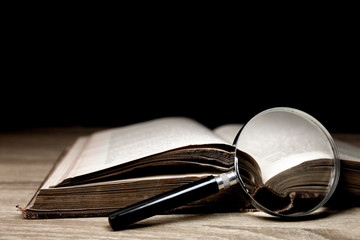 Magnifying glass on books with wooden background