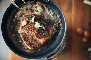 Overhead shot of chef preparing ribeye with butter, thyme and garlic. Keto diet.