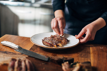 Female chef serving ribeye steak and cleaning the plate