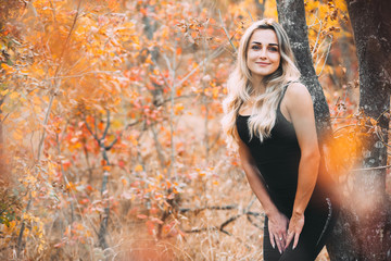 Beautiful attractive girl posing in autumn forest in black pants and t-shirt with beautiful white...