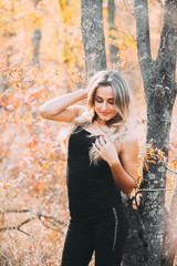 Beautiful attractive girl posing in autumn forest in black pants and t-shirt with beautiful white hair