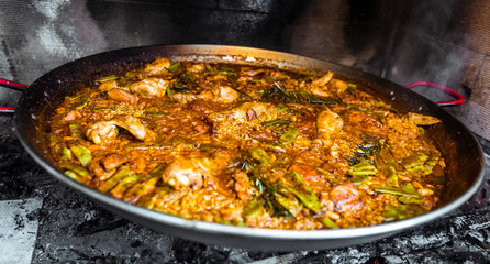Cooking and making a traditional Spanish Paella over open fire.