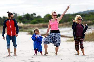 Portrait of happy family and friends walking on the beach.