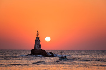 Fiery sunrise. Lighthouse, fisherman boat and sunrise. Black Sea, Ahtolol, Bulgaria.