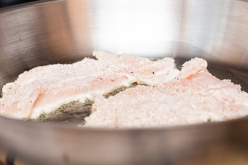 Raw chicken fillet fried in a pan in oil