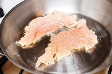 Raw chicken fillet fried in a pan in oil