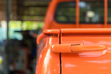 A classic vintage orange pick-up vehicle is parking in local garage. Close up and selective focus...