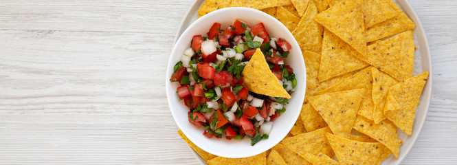 Pico de Gallo with gluten free tortilla chips on a white wooden background, top view. Flat lay,...