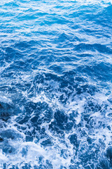 Fototapeta na wymiar Background blue waves of the sea with sea foam