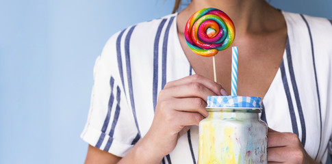 Front view of a woman holding a milkshake and lollipop