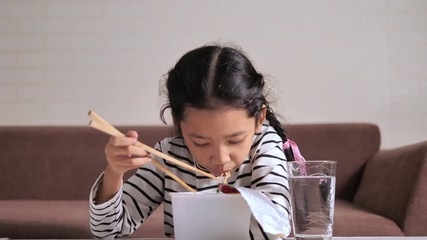 Little Asian girl eating instant noodle with happiness select focus shallow depth of field