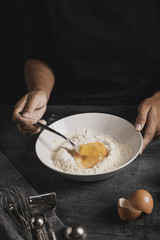 High angle baker hands mixing flour with egg