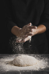 Front view baker spreading flour on dough composition