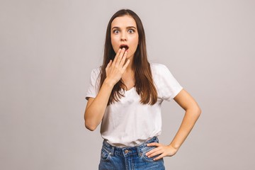 Portrait of amazed shocked young woman looking at camera isolated over a grey background.