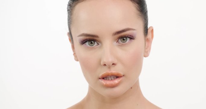 Beautiful healthy  woman touches her neck with hands.  Closeup face of young woman.  Beautiful girl with  sexy look looks to the camera. Slow motion