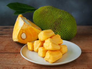 Ripe jackfruit flesh in a white plate on a wooden table for tropical fruit or meat substitute...