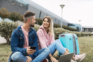 Traveling. Couple Using Phone, Waiting Transport Near Airport