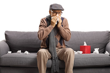 Elderly gentleman sitting on a sofa and blowing his nose