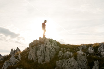 Athletic hiker standing on the mountains ridge during the sunset.