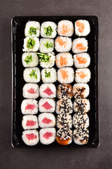 Sushi set compositionally located on a dark surface.