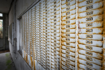 Rostige Wandhalterung mit Nummerierung für Stempelkarten in einem verlassenen Fabrikgebäude