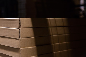 brown goods carton boxes in warehouse storage factory . abstract pattern and texture of cargo in black background with light and shadow , retail and wholesale concept .