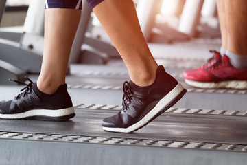 Side view of young girl running in machine treadmill at fitness gym