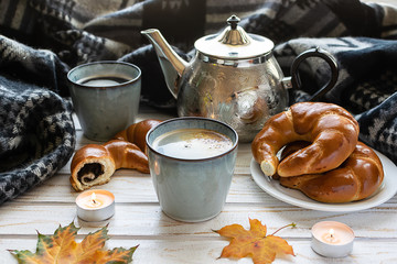 Hygge style autumn composition with two cups of aromatic coffee, vintage kettle, warm blanket, aromatic pastry and dessert. Vintage composition.