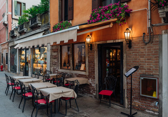 Old street with tables of restaurant in Venice, Italy. Architecture and landmark of Venice. Cozy...