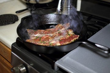 Korean style BBQ short ribs, known as Kalbi, on a cast iron skillet in a home kitchen.