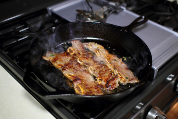 Korean style BBQ short ribs, known as Kalbi, on a cast iron skillet in a home kitchen.