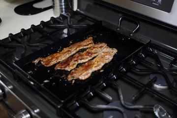 Korean style BBQ short ribs, known as Kalbi, on a carbon steel griddle in a home kitchen.