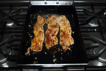Korean style BBQ short ribs, known as Kalbi, on a carbon steel griddle in a home kitchen.