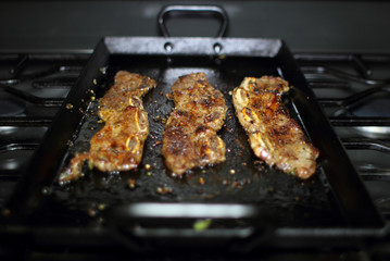 Korean style BBQ short ribs, known as Kalbi, on a carbon steel griddle in a home kitchen.