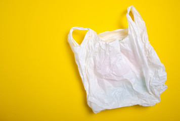 Clear disposable plastic bag on yellow background. Space for text