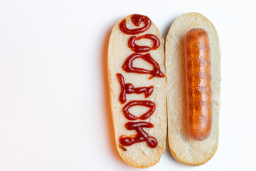 Hot sandwich with sausage on white background with space for text.Text the ketchup hot dog on the bread. Top view. Copy space