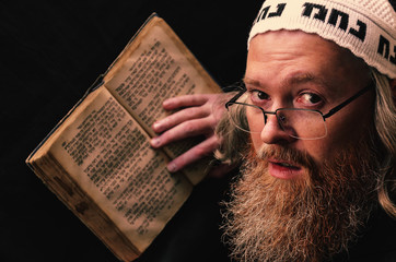 A Hasidic Jew reads Siddur. Religious orthodox Jew with a red beard and with pace in a white bale...
