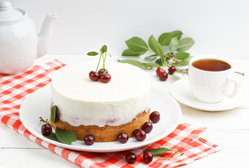 Homemade cherry pie with delicate yogurt filling and cup of tea on white wooden table. Shallow focus.
