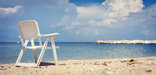 Empty beach chair by the sea with stormy clouds in the background
