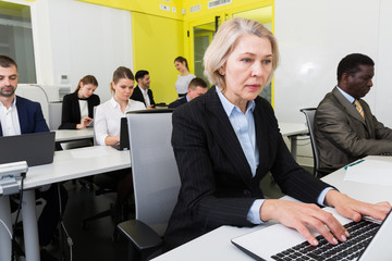 Mature female working in open plan office