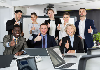 Group of international business people holding thums up in office