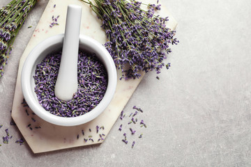 Top view of mortar and pestle with lavender flowers on grey stone background, space for text....