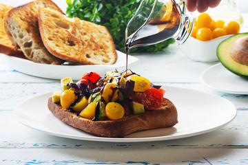 Bruschetta with avocado, tomatoes and  basil with balsam sauce. Close up. Selective focus.