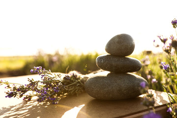 Obraz na płótnie Canvas Stack of spa stones on wooden table in lavender field. Harmony and zen