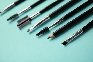 Fototapeta premium Set of professional eyebrow tools on turquoise background