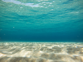 Clear water. Underwater background with sandy sea bottom.